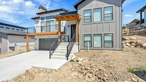 Une maison moderne à deux étages, dotée d’un garage, d’un porche couvert et d’un escalier menant à l’entrée.