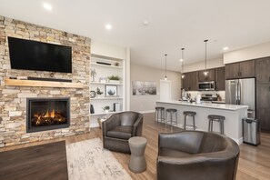 Una sala de estar moderna con chimenea de piedra, sofás de cuero y un televisor de pantalla plana.