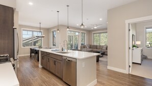 Une cuisine moderne dotée d’un îlot central, de meubles en bois et de luminaires suspendus.