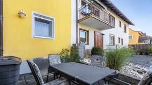 Un patio con tavolo e sedie, un edificio giallo e un balcone.