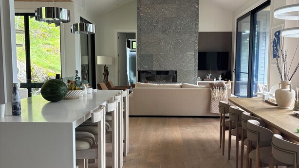 A modern kitchen with a central island, wooden flooring, and a stone accent wall. - Luxury cottage (Port Carling)