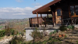 A wooden cabin with a balcony overlooking a scenic landscape.