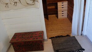 A room with a wooden desk, a red patterned box, and a woven rug.