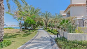 A pathway lined with palm trees and a view of the sea. - Vogue | Palm Jumeirah with Access to Private Beach (Dubai)
