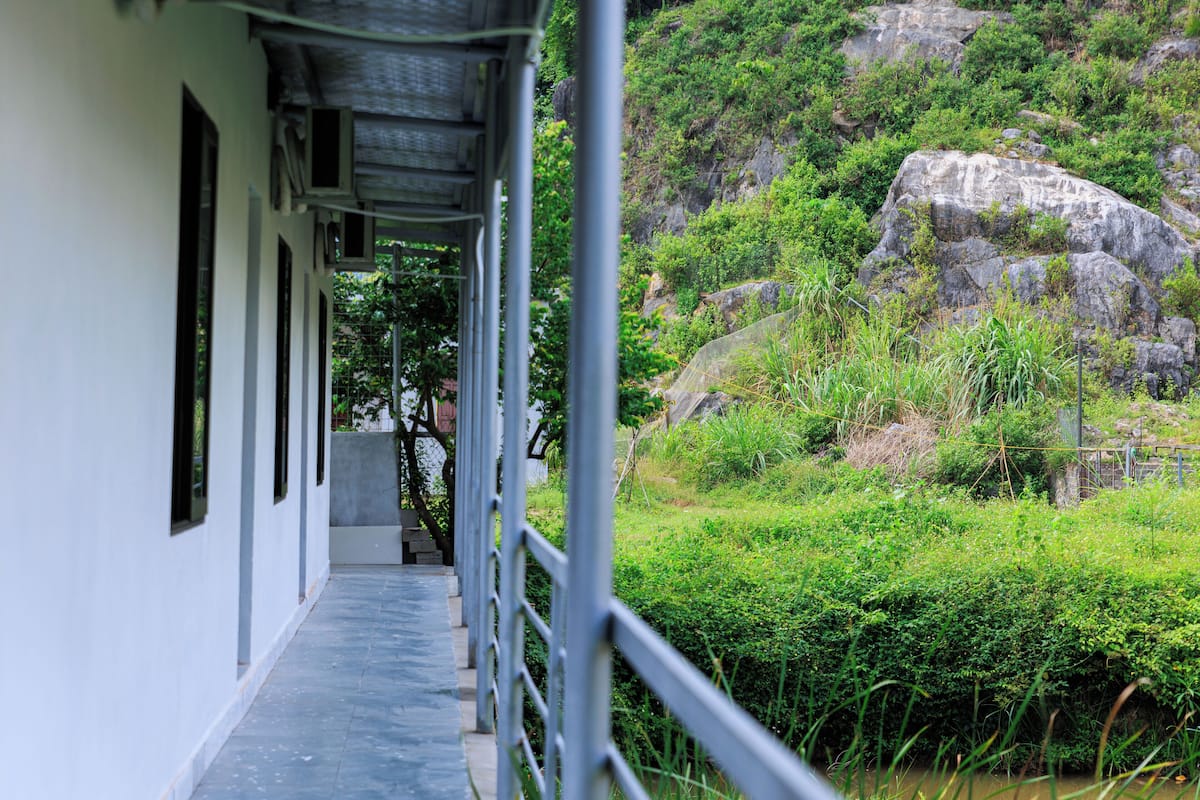 A corridor with a view of a rocky hillside and greenery.