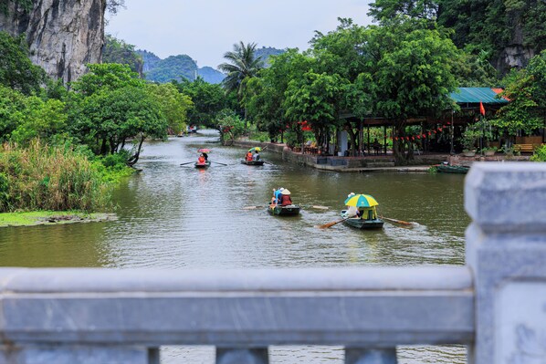 A river with boats and a bridge in the foreground. - Heartfelt Hideaway (Nam Hoa Lu)