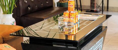 A living room with a glass coffee table, a sofa, a plant, and a speaker system.