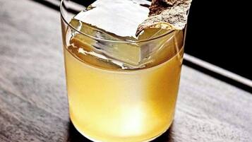 A glass with a clear liquid and a piece of brown toast on the rim.