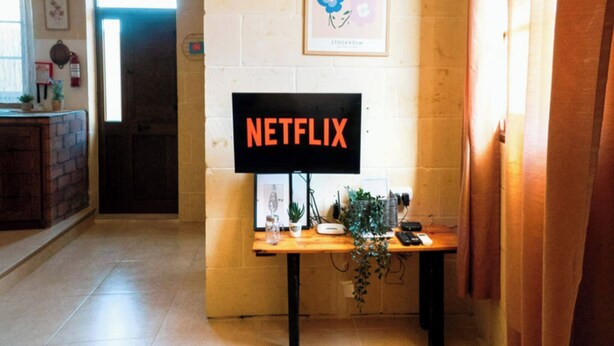 A hallway with a wooden table displaying a sign that reads "NETFLIX" and a poster of flowers. - Kampanjola in Dahlet Pawluzzu (San Lawrenz)