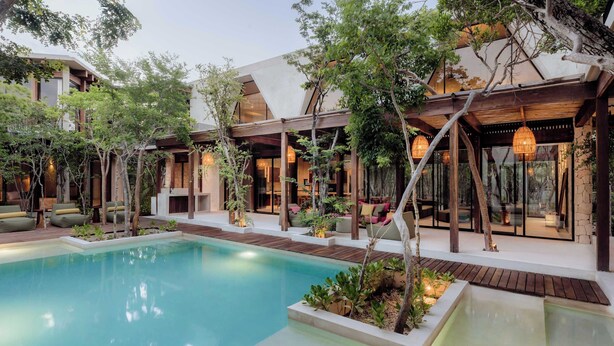 A modern resort with a pool, outdoor seating, and a mix of wooden and glass structures.