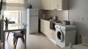 A modern kitchen with a dining area, a washing machine, and a dining table with chairs. - Silv apartment3 Preveza city center (Preveza)