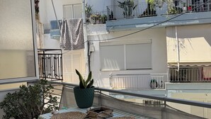 A balcony with a checkered tablecloth, two woven placemats, a potted plant, and two chairs. - Silv apartment3 Preveza city center (Preveza)