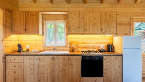 A wooden kitchen with a built-in dishwasher, a stove, and a refrigerator.