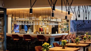 Zona de bar moderna amb diverses opcions de seients, incloent tamborets i taules, i una varietat d'estris i ampolles de bar.