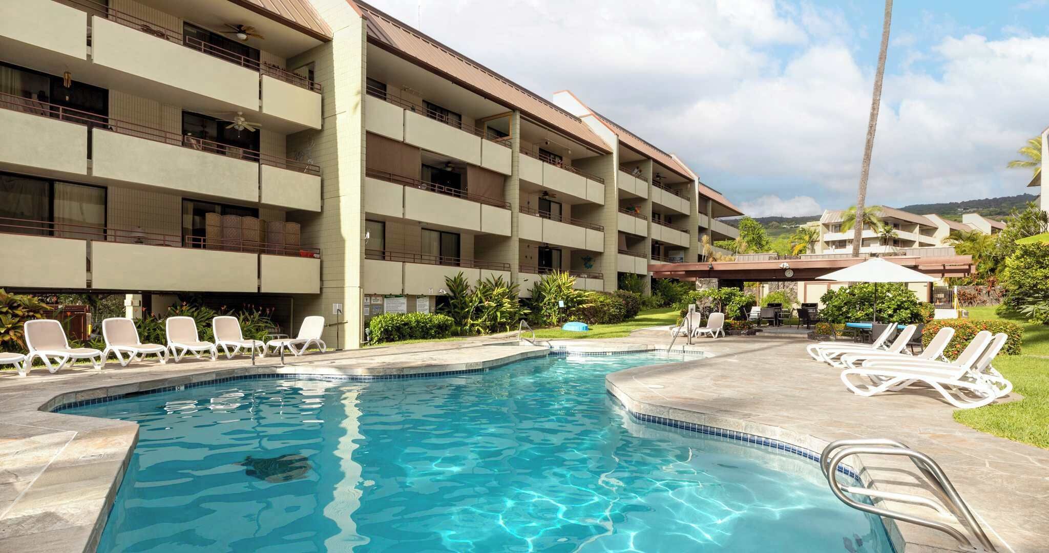 A hotel with a swimming pool, multiple balconies, and outdoor seating areas.