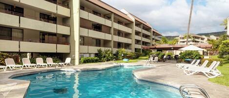 A hotel with a swimming pool, multiple balconies, and outdoor seating areas.