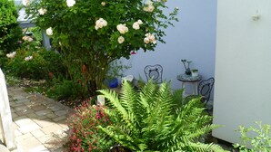A garden with roses, ferns, and a small table with chairs. - Apartment 'Loft Straussi' with Shared Garden and Wi-Fi (Tuttlingen)