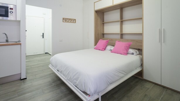 A bedroom with a bed, a built-in wardrobe, a microwave, and a small kitchenette. - Apartment in Las Palmas Near Playa de Las Canteras (Las Palmas de Gran Canaria)