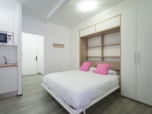 A bedroom with a bed, a built-in wardrobe, a microwave, and a small kitchenette. - Apartment in Las Palmas Near Playa de Las Canteras (Las Palmas de Gran Canaria)