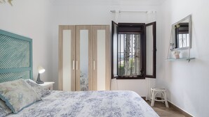 A bedroom with a bed, a nightstand, a window with curtains, a mirror, and a wardrobe. - Apartment 'Arroyuelo' with Mountain Views, Wi-Fi and Air Conditioning (Prado del Rey)