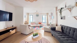 A modern living room with a flat-screen TV, a sofa, a coffee table, and a TV stand.