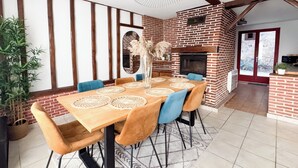 A dining area with a brick fireplace, a large mirror, and a potted plant.