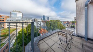 Une terrasse sur le toit offrant une vue sur le paysage urbain, avec des bâtiments modernes et un ciel dégagé.
