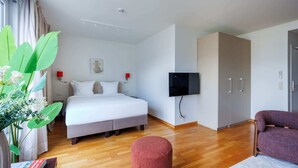 Une chambre d’hôtel comprenant un lit, une télévision, une armoire et un coin salon.