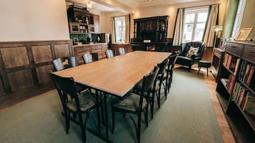 A dining area with a wooden table and chairs, a dark wooden cabinet, and a bookshelf.