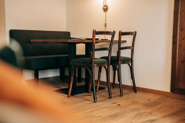 Un coin repas comprenant une table en bois, deux chaises et un canapé.