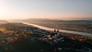 Vista aérea de un pueblo con una iglesia destacada, un río y colinas circundantes.