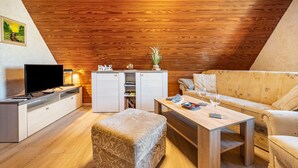 A cozy living room with a wooden ceiling, a flat-screen TV, a sofa, a coffee table, and a small cabinet. - Holiday Appartment "Anne" with Balcony and Wi-Fi (Bremervörde)