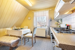 A kitchen with a dining table, chairs, a radiator, and a stove.