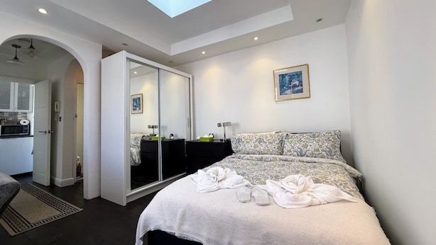 Une chambre d’hôtel moderne avec une lucarne, un lit avec des serviettes, un miroir et une petite kitchenette.