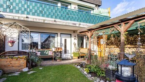 Ein Wohnhaus mit gepflegtem Garten, einer Holzterrasse und einer sichtbaren Haustür.