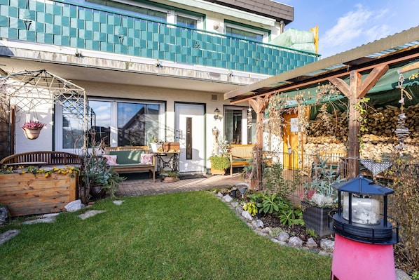 Il s’agit d’une propriété résidentielle dotée d’un jardin bien entretenu, d’une terrasse en bois et d’une porte d’entrée bien visible.