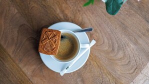 A cup of coffee with a biscuit on a saucer on a wooden table. - Suite Mas B-42 Studio - Split Level (Brussels)