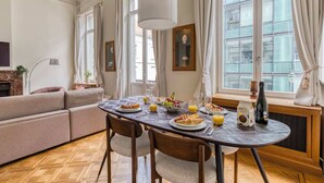 A dining area with a table set for breakfast, including croissants, waffles, and fruit.