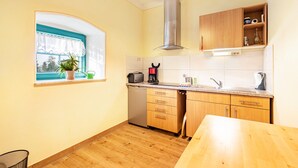 Une cuisine avec des meubles en bois, un lave-vaisselle encastré, une fenêtre avec vue et un luminaire au plafond.