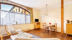 Une pièce confortable avec un lit, un bureau, une chaise, une télévision et une fenêtre avec des rideaux.