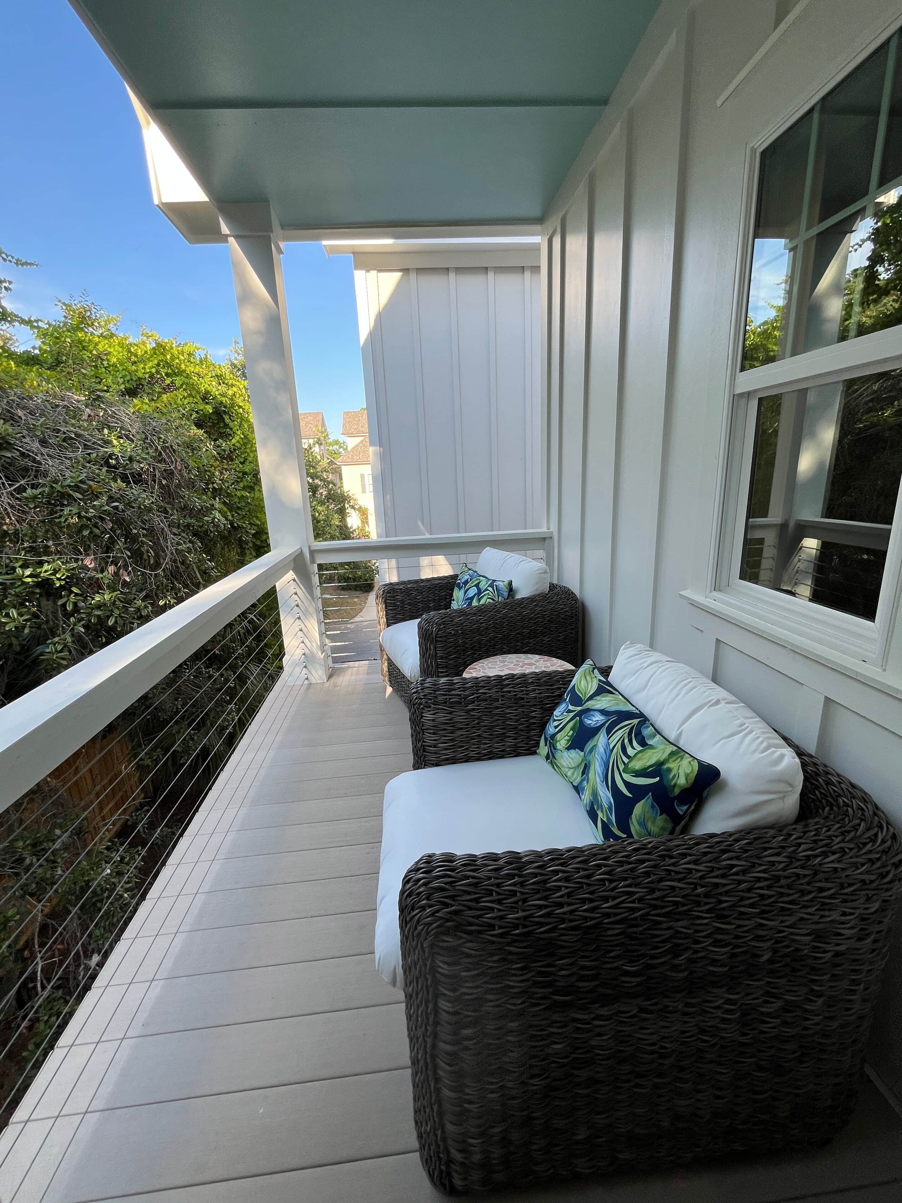 A covered porch with wicker furniture and a white railing.