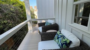 A covered porch with wicker furniture and a white railing.