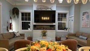 A living room with a TV, sofas, a dining table, and a chandelier.