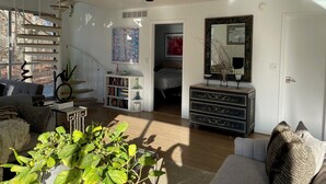 A spacious living room with a staircase, a bookshelf, a dresser, and a large mirror. - 3-bedroom house in awesome East Hampton with AC, WiFi, backs up to county park (East Hampton)