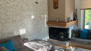 Un salon avec un mur en briques, une cheminée, un canapé et une table basse.