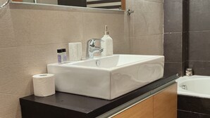 Une salle de bain moderne avec un lavabo blanc, un plan de travail noir et des meubles en bois.