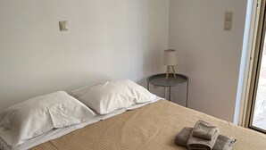 Une chambre à coucher avec un lit, des oreillers, une table de chevet avec une lampe et des serviettes sur le lit.