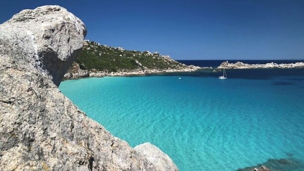 A coastal landscape with clear turquoise waters, rocky formations, and a sailboat. - Apartment Rena Bianca IUN S4020 (Santa Teresa Gallura)