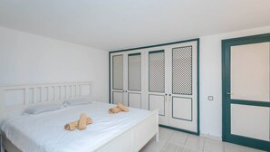 Un dormitorio con cama, cabecera blanca y un conjunto de puertas con paneles decorativos.