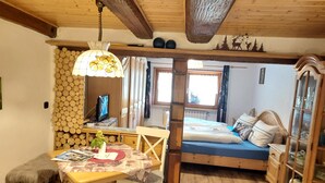 Ein gemütliches Zimmer mit einem Bett, einem Schreibtisch mit Lampe, einem Sessel und einem Fenster.